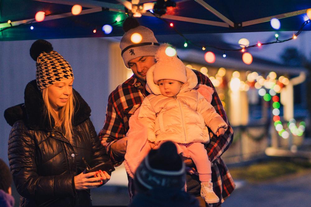 family standing under a lit tent at dusk 