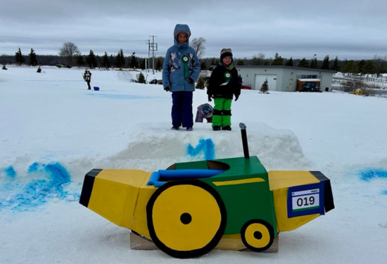 award winners standing next to winning cardboard toboggan shaped like the banana